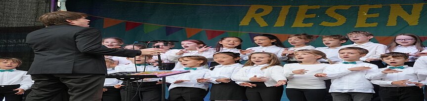 Kinderchor mit Dirigent auf der Bühne des Kidz Riesenkinderfestes