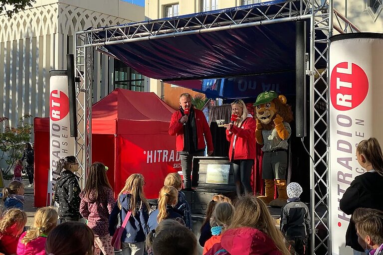 Bühne Hitradio RTL im Konzertgarten mit Moderatoren Uwe Fischer und Katja Möckel sowie Zoomaskottchen Löwe Tammi, davor Besucher