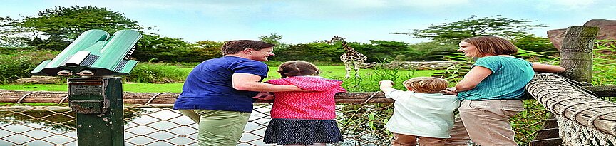 Familie auf Besucherantritt vor der Kiwarasavanne mit Blick auf Giraffen