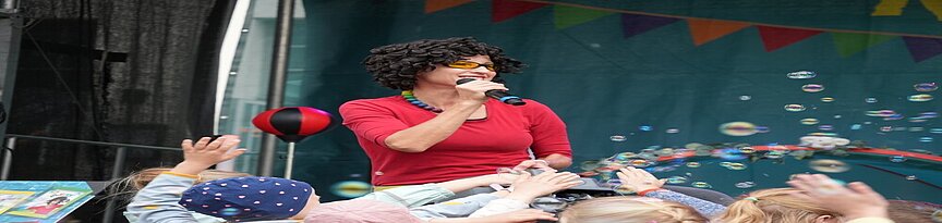 Kinderliedersängerin KESS auf der Bühne vor Kindern mit Seifenblasen